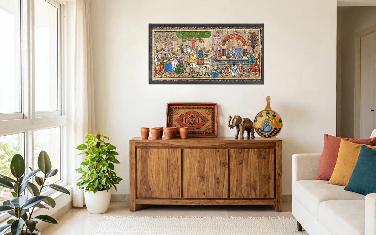 Handcrafted housewarming gifts on a wooden table at a new home entrance: terracotta tea cups, a painted wooden tray, a pattachitra painting and a Dhokra brass figurine